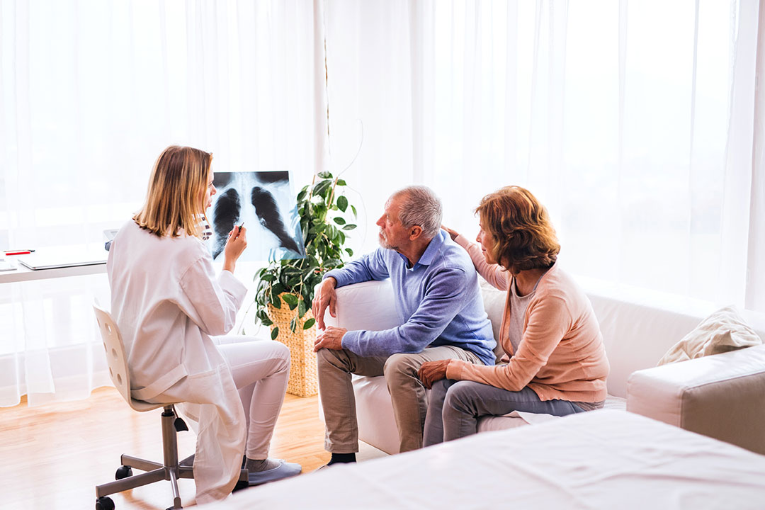 female-doctor-with-x-ray-talking-to-a-senior-coupl-PYVXX4E